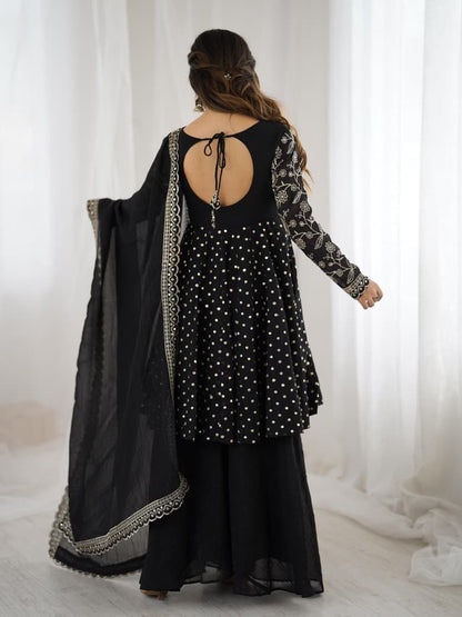 Woman wearing a black traditional outfit with a sheer dupatta against a white curtain background Black Sharara Suit Set Roorhi