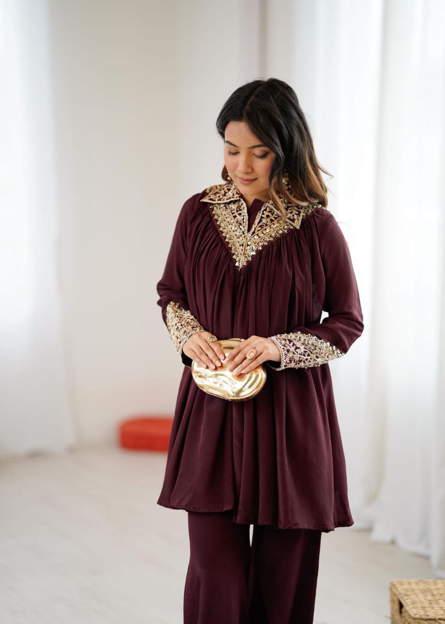 Woman wearing a burgundy outfit with gold embellishments in a bright room. Co-ord Set Roohri

