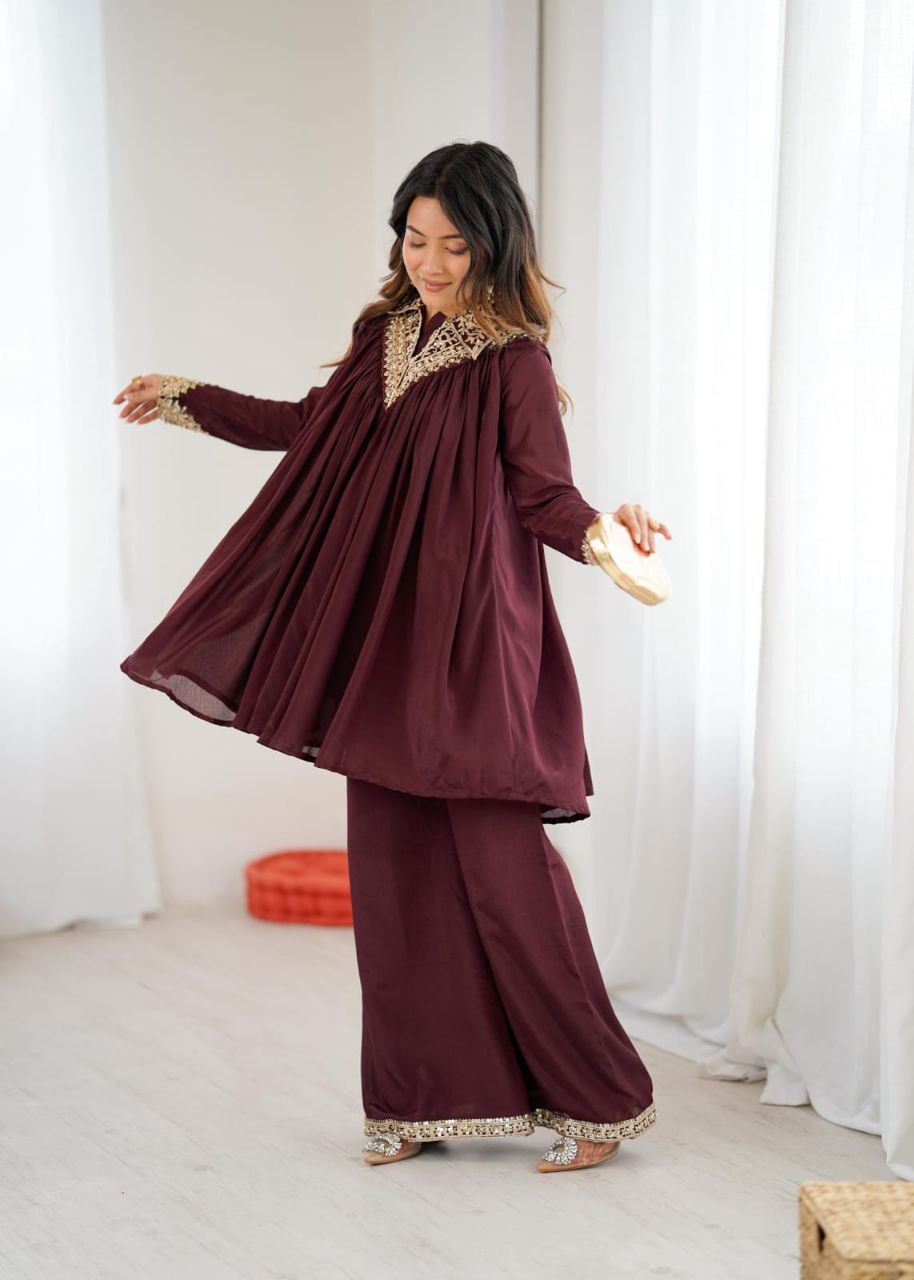 Woman wearing a burgundy traditional outfit with gold embroidery in a white room. Co-ord Set Roohri