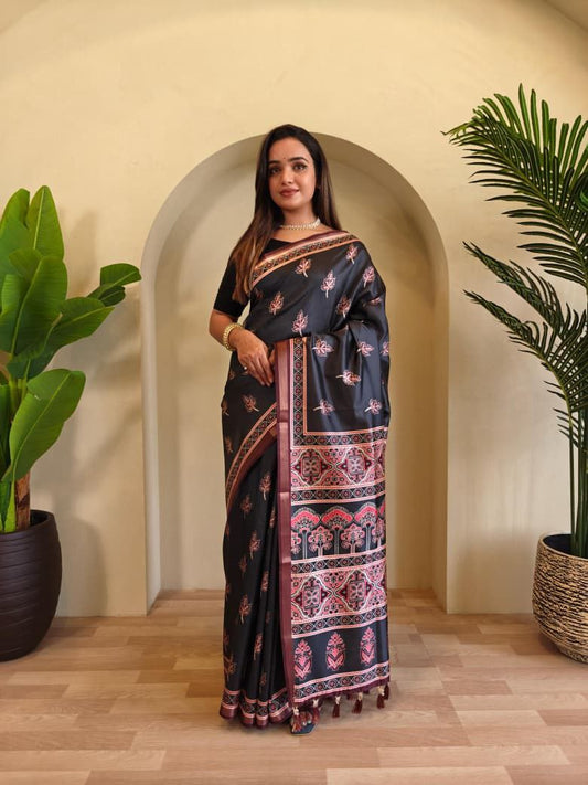 Woman wearing a black saree with pink patterns standing in a room with plants.  Dola Viscose Saree Roohri