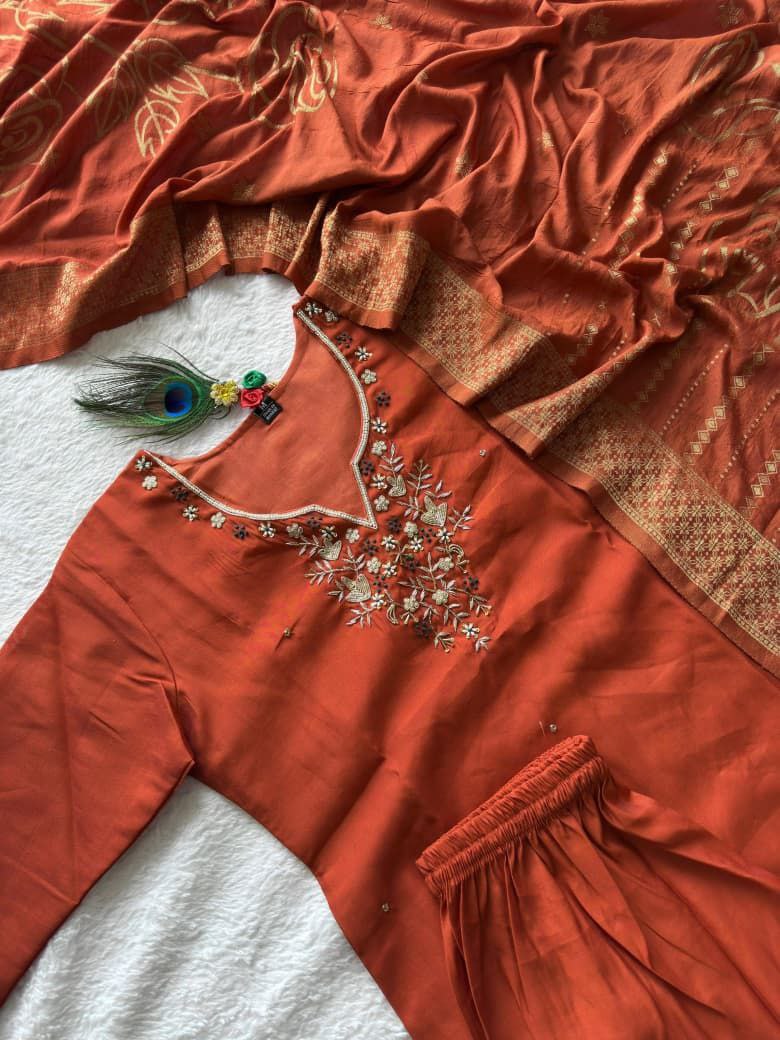 Orange saree with intricate embroidery and a peacock feather brooch on a white background Orange hand embroidered suit set Roohri