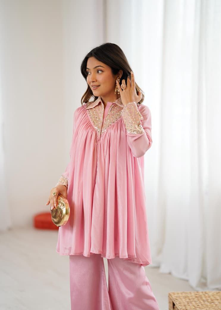 Woman wearing a pink outfit with gold accents in a bright room. Pink Co-ord Set