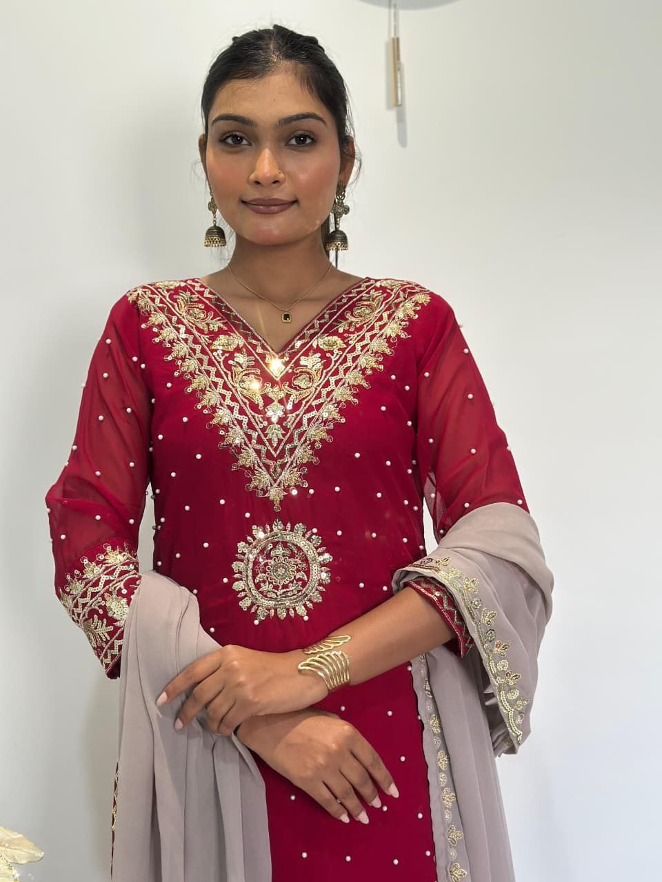 Woman wearing a red embroidered traditional outfit with a plain background Red Palazzo Suit Set Roohri