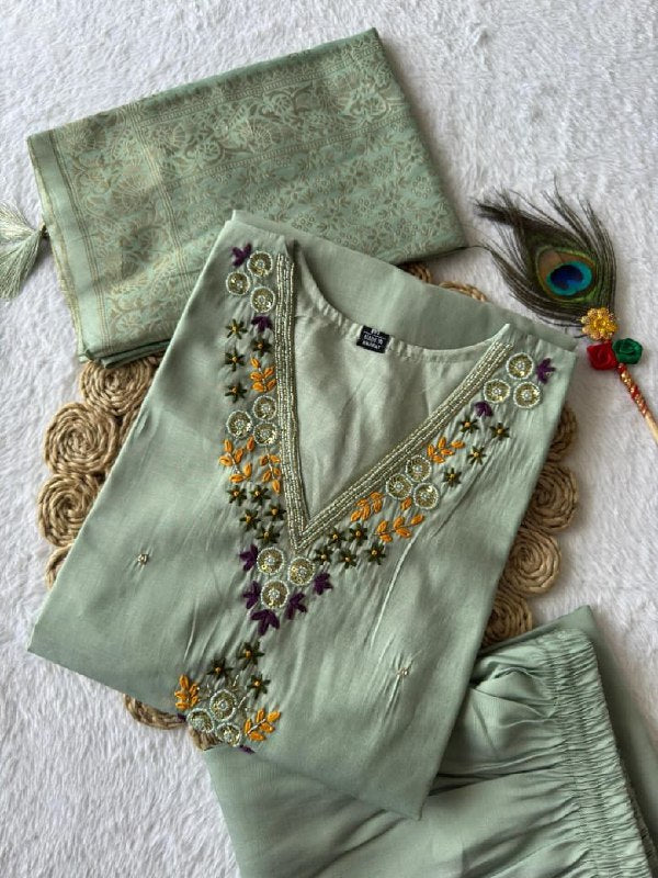 Light green embroidered outfit with a decorative clutch on a textured sea green suit set roohri surface.
